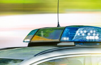 Dach eines Polizeiauto mit Blaulicht vor verschwommenem Hintergrund | © Foto: AdobeStock #203049376 | jozsitoeroe