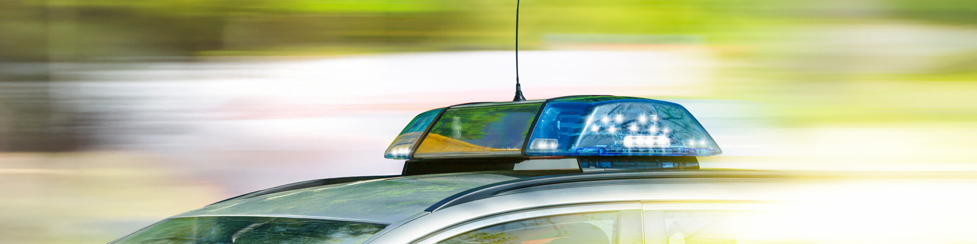 Dach eines Polizeiauto mit Blaulicht vor verschwommenem Hintergrund | © Foto: AdobeStock #203049376 | jozsitoeroe